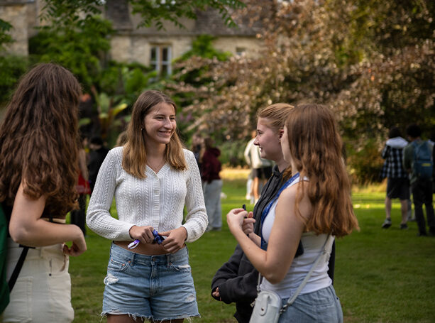 Four students at Oxford standing together on the green.