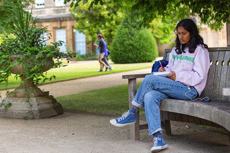 student-writing-on-bench-outside-oxford