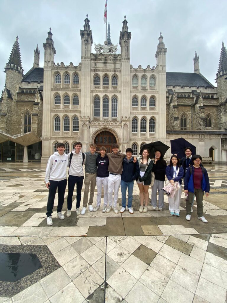 students smile in a group photo in front of London's Guildhall