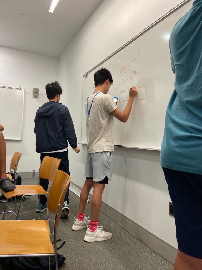 two students writing on dry erase board