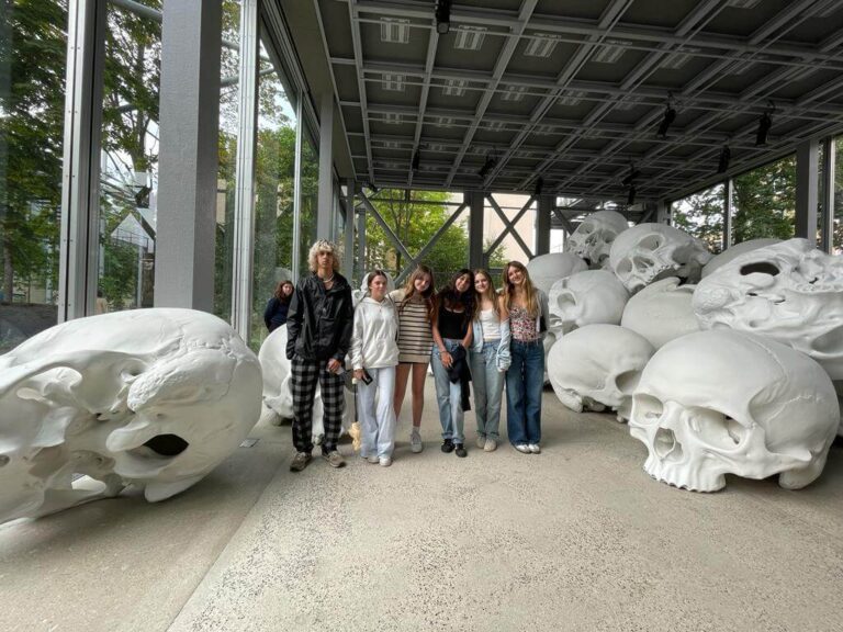 students standing at art exhibit of huge skull statues