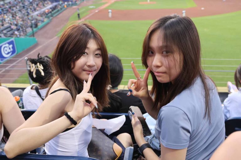 Two student look back over their seat holding up peace signs