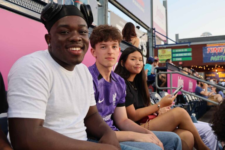 Student sitting in stadiun seats smile at camera