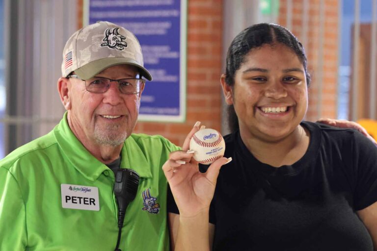 Student holidng up baseball poses for picture with baseball coach