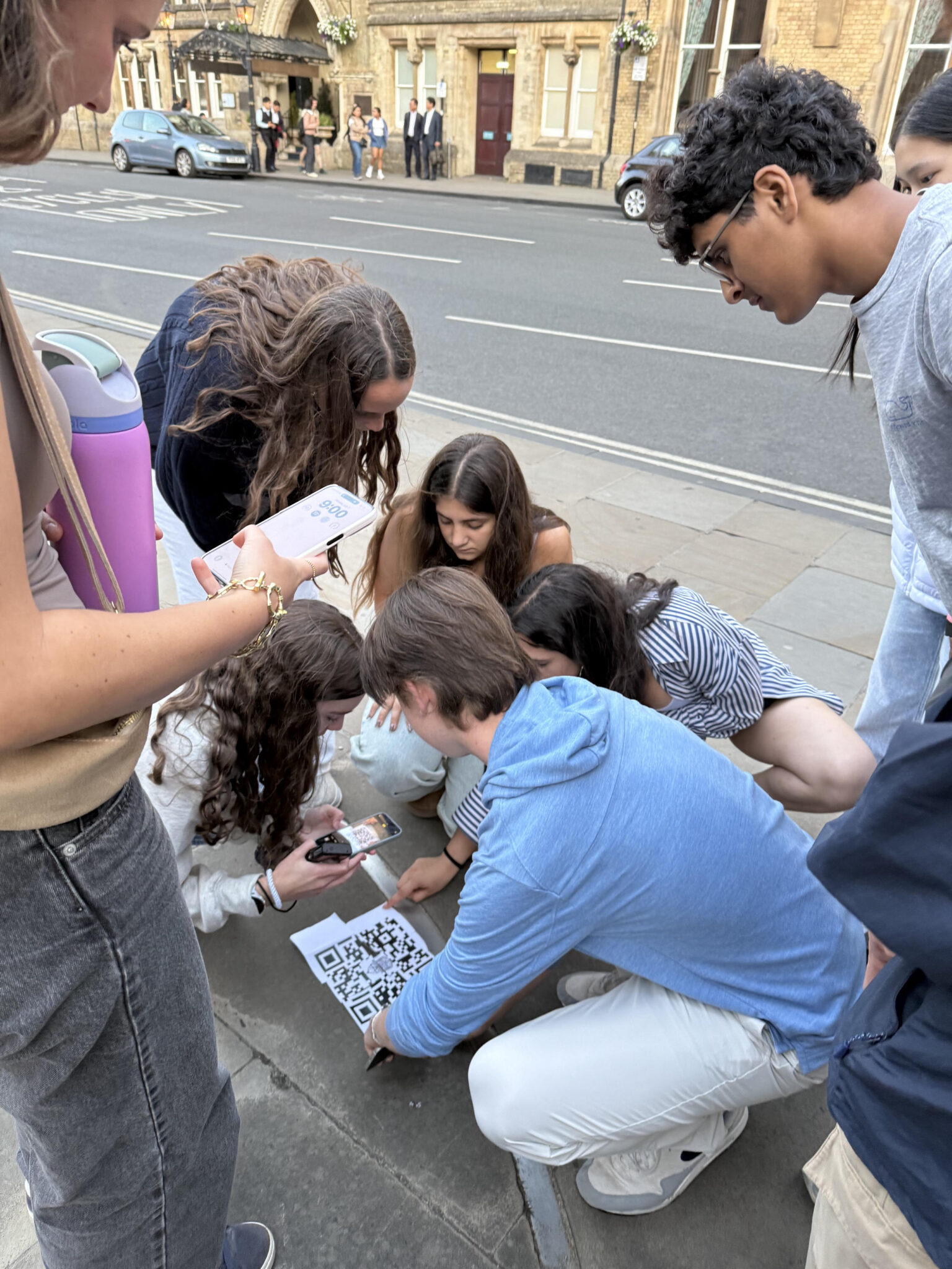Students stand over piece of paper with QR code