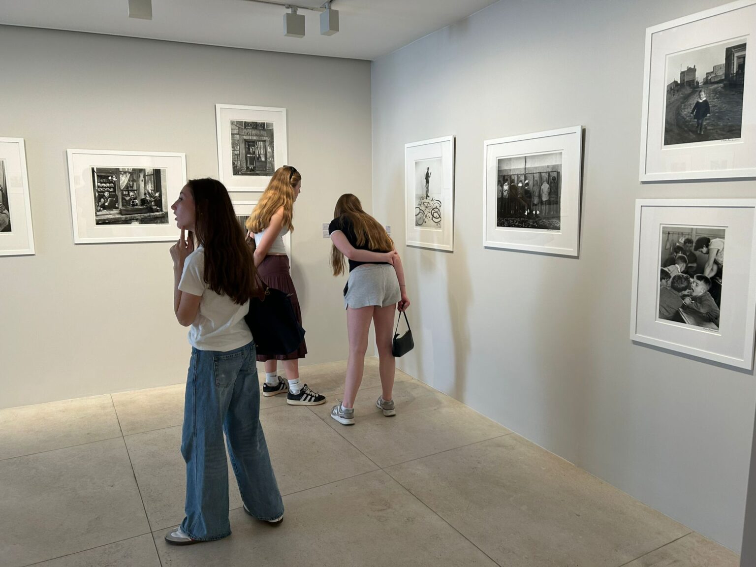Three students look at black and white photographs on display