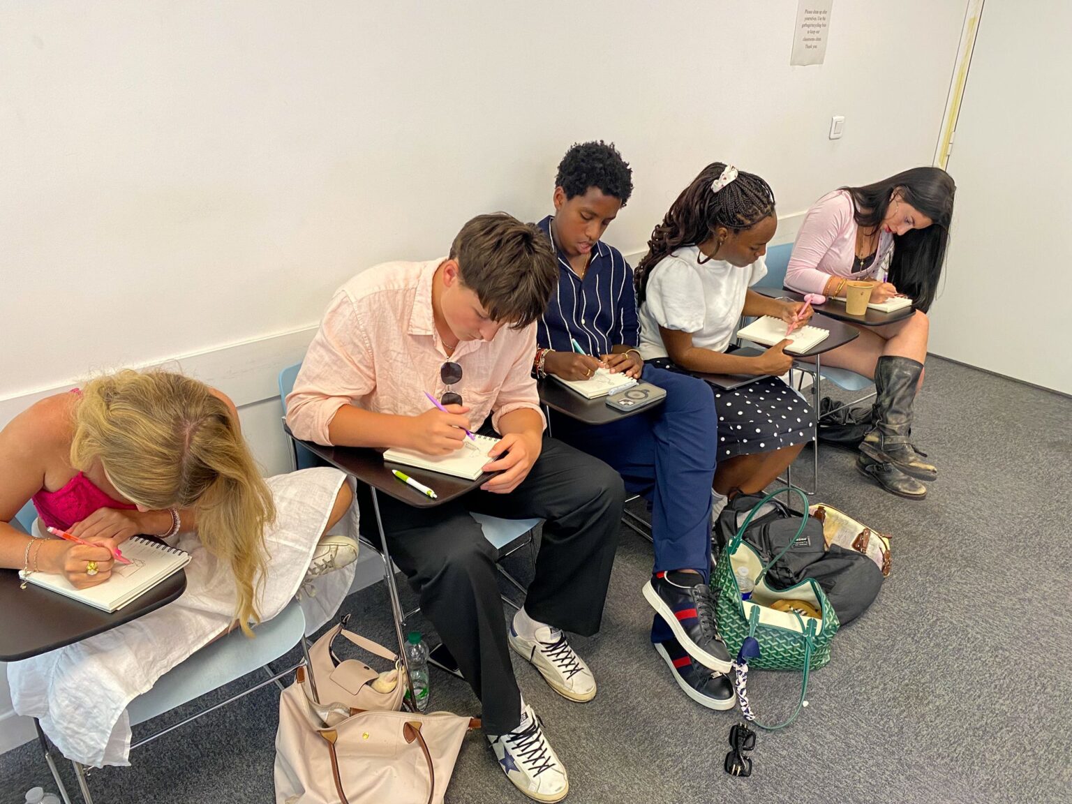 Student hunch over notebooks drawing designs
