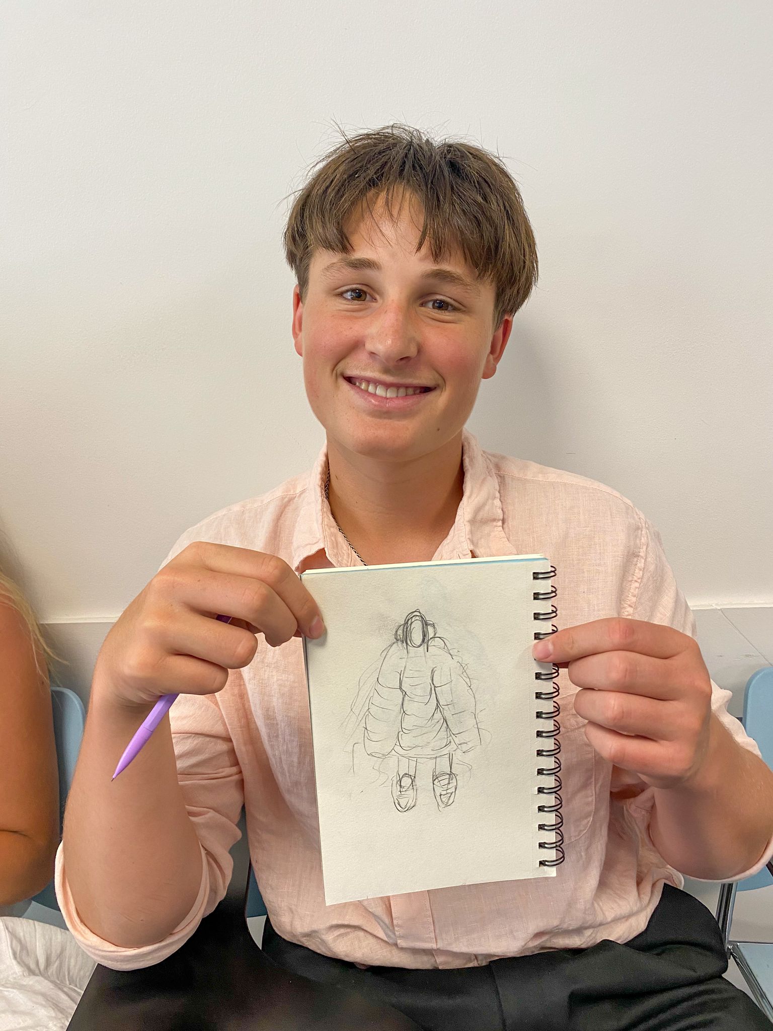 Student holds up sketch of clothing design