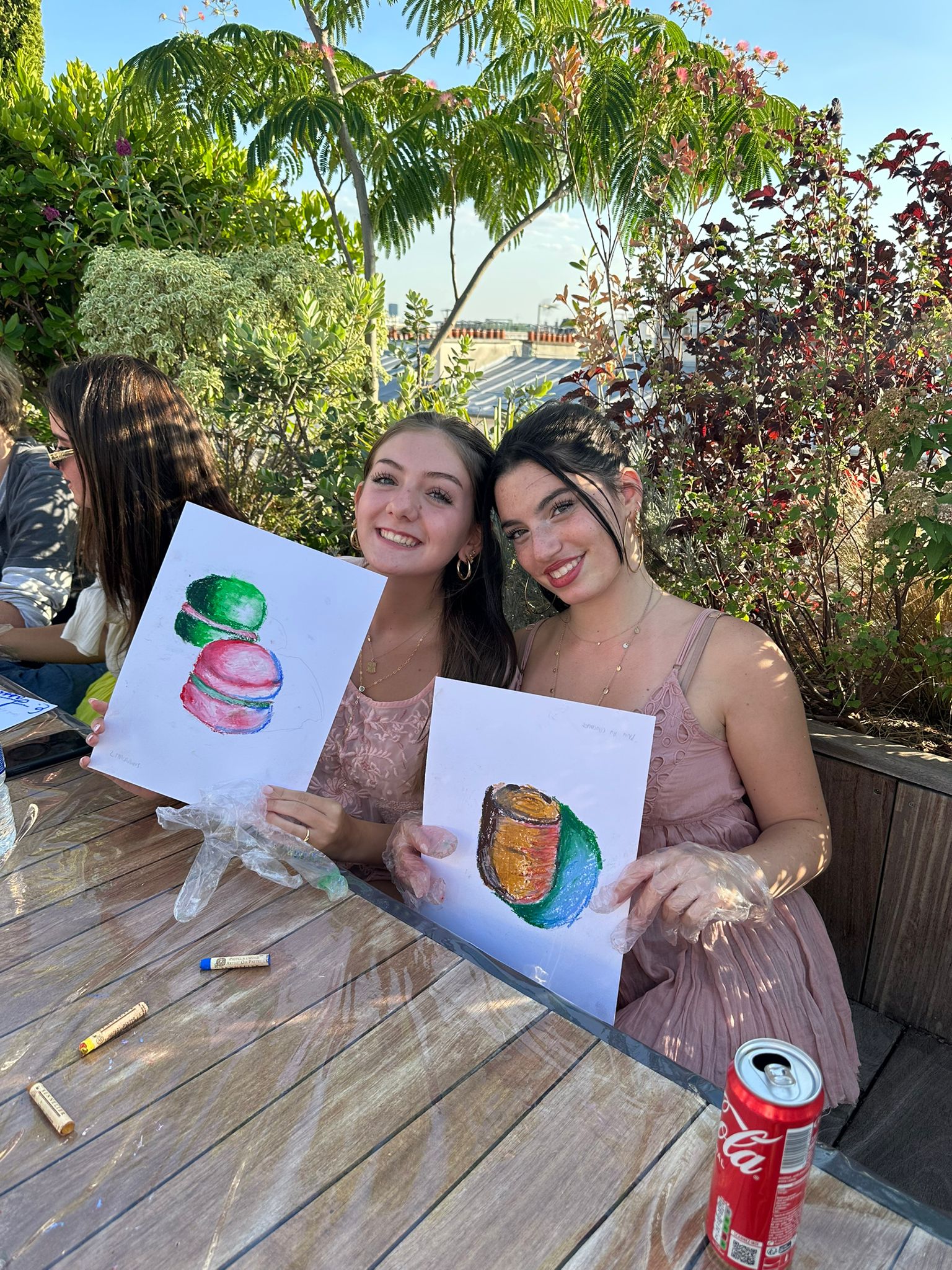 Two student sit together holding up their completed oil pastel paintings