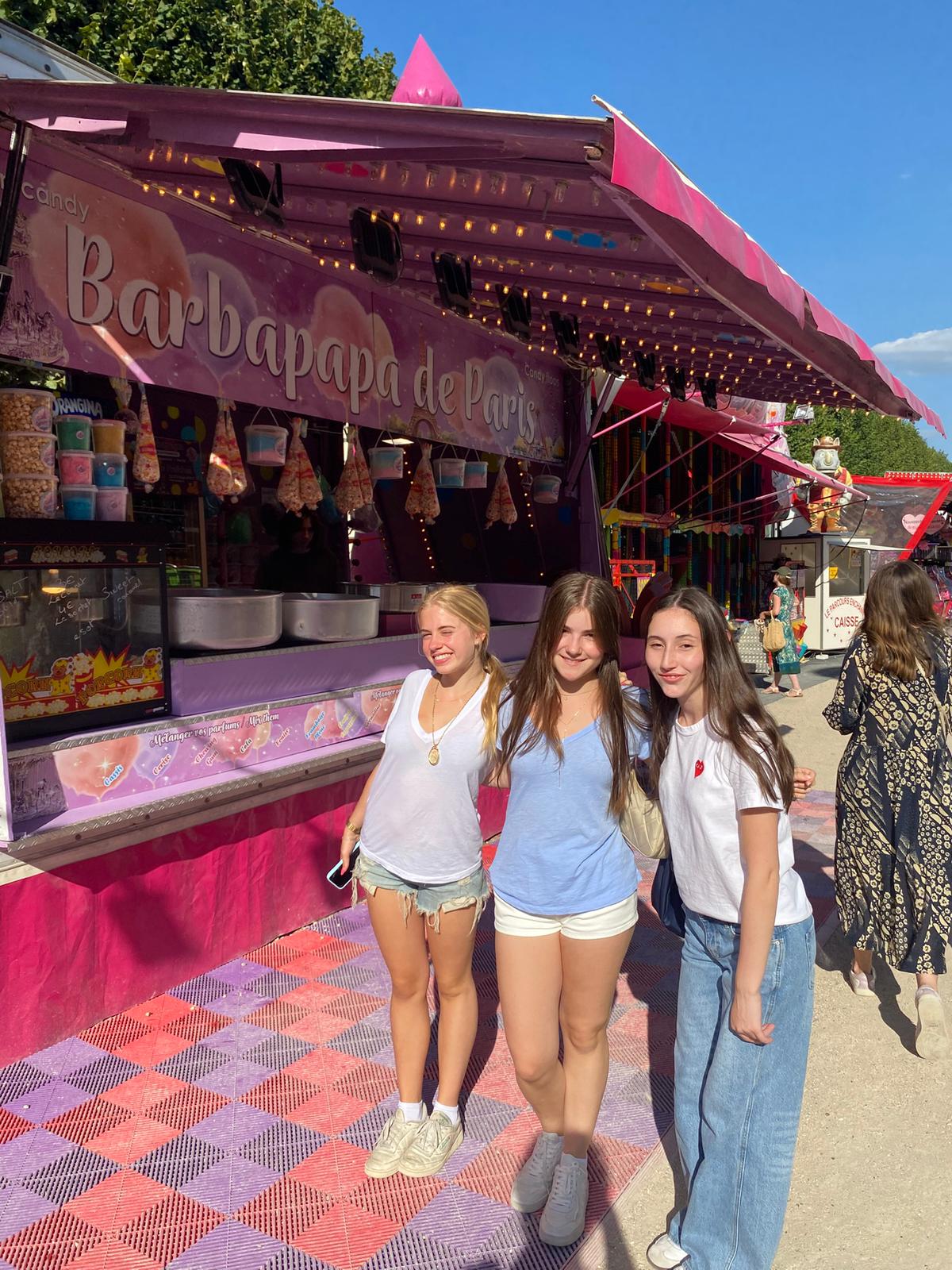 Three students pose of picture together in front of a carnival stand