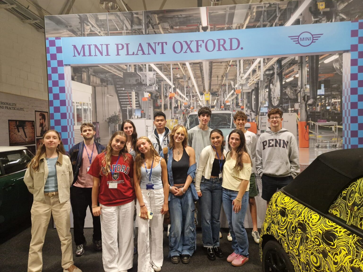 Group photo of student posing with cars at MINI Factory in Oxford