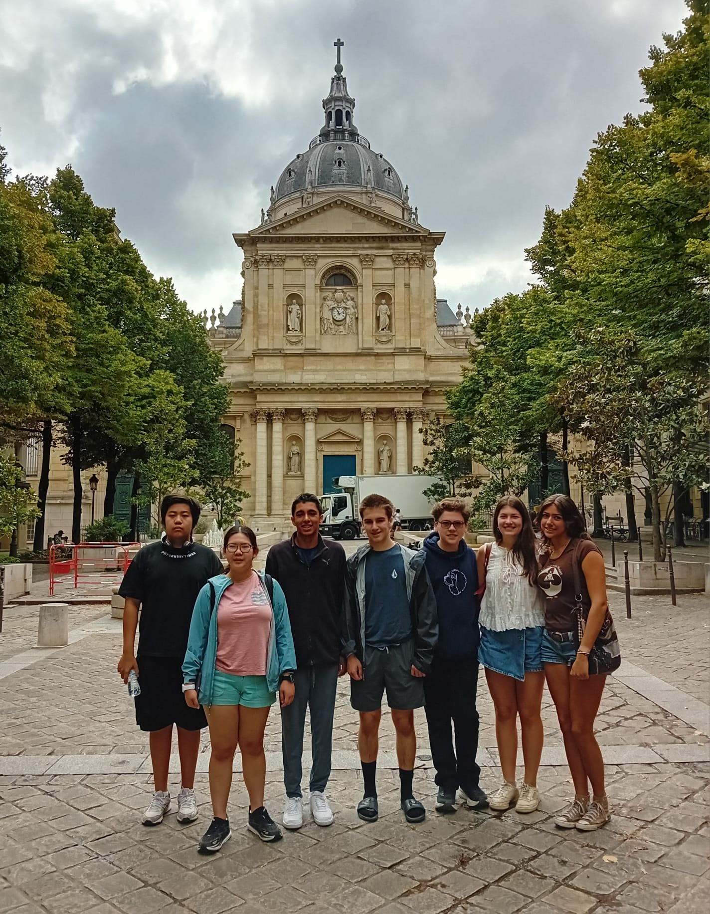 Students pose for group photo on front of historic building in Paris