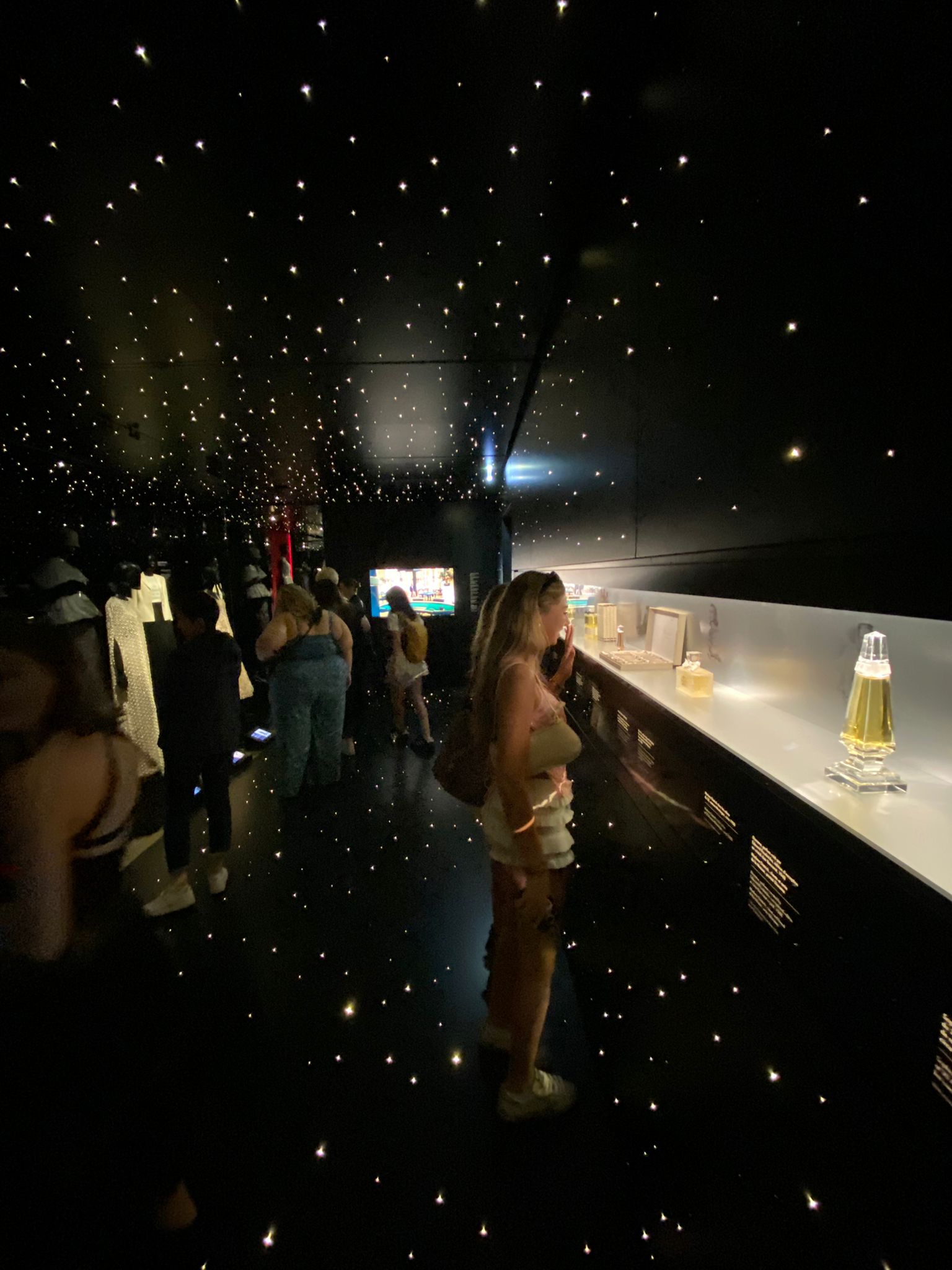 Student looks at fashion display in dark room with stars
