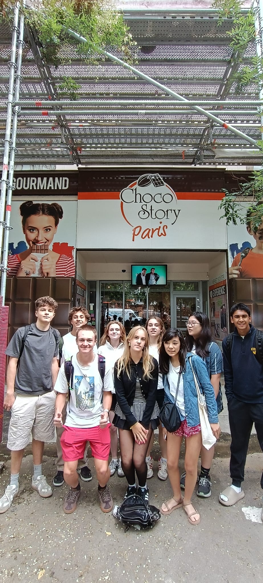 Students pose for group photo in front of "Choco Story" building